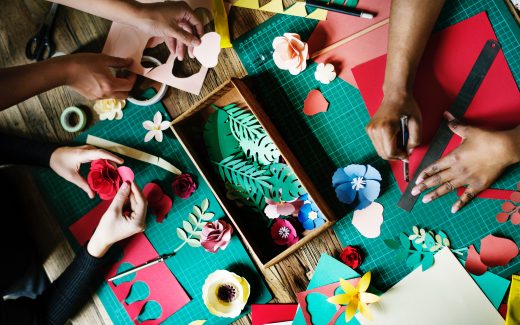 Hands working together on a collaborative green and red craft project. I'll do it my way