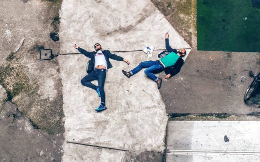 Two men lying spreadeagled on a cracked piece of concrete. And this, too, shall pass